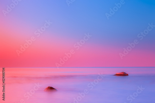 Romantic pink sky over rocks in Baltic Sea at sunrise, Lithuania
