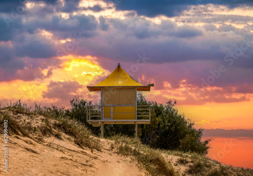 Dramatic sunset over a Lifeguard hut in sand dunes on a beach, Queensland, Australia photo