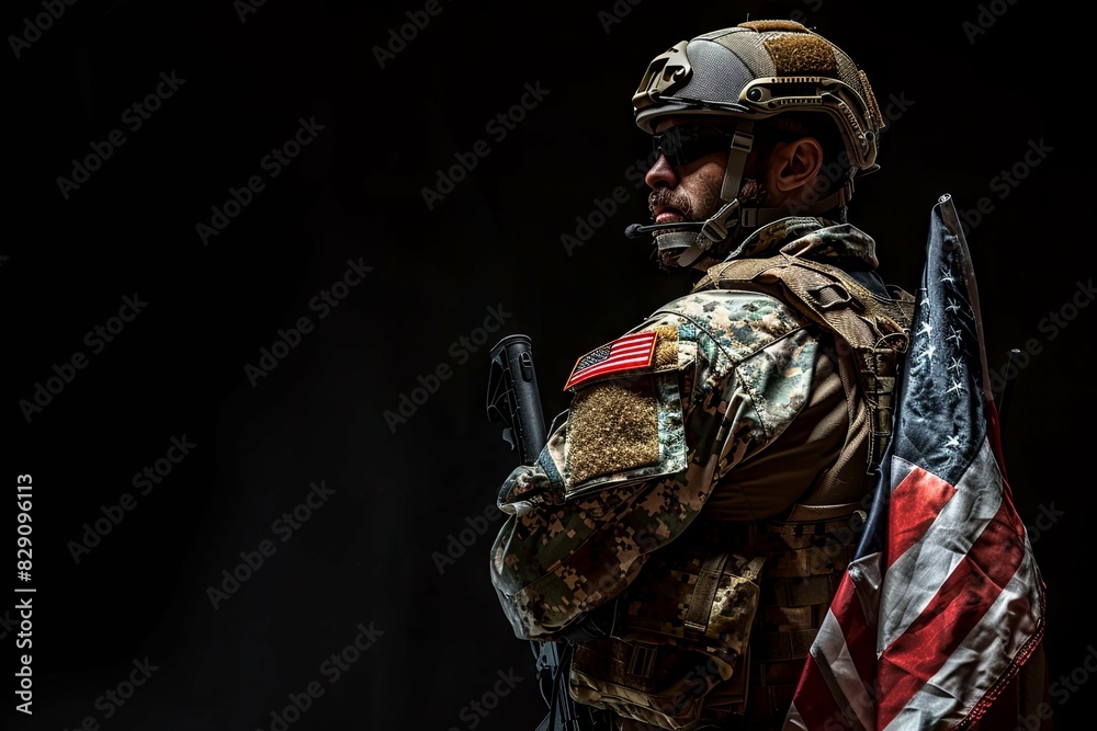 A soldier in full combat gear stands with an American flag draped over ...