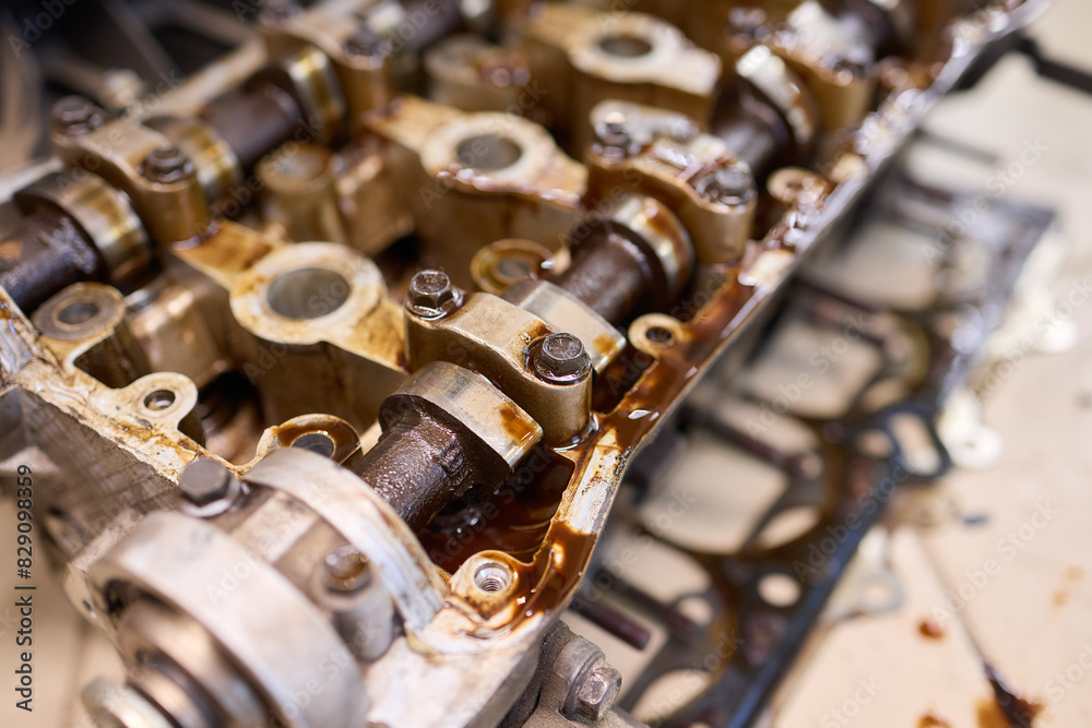 Dirty engine head on tiled floor with scattered parts Dirty engine head on tiled floor with scattered parts