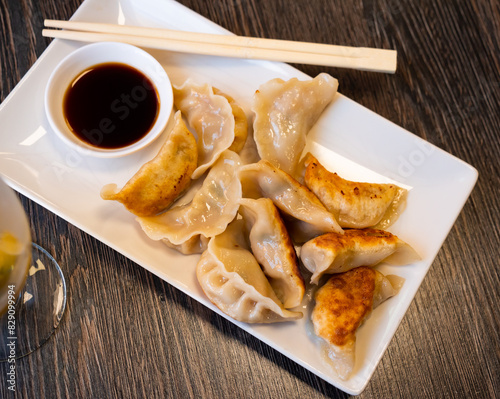 Foto Delicious fried Chinese dumplings served with bowl of soy sauce on plate