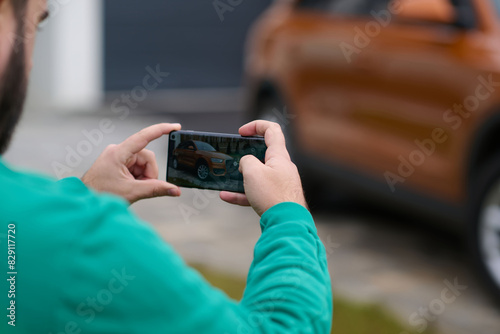 man taking photos on a smartphone of a car preparing for sale 