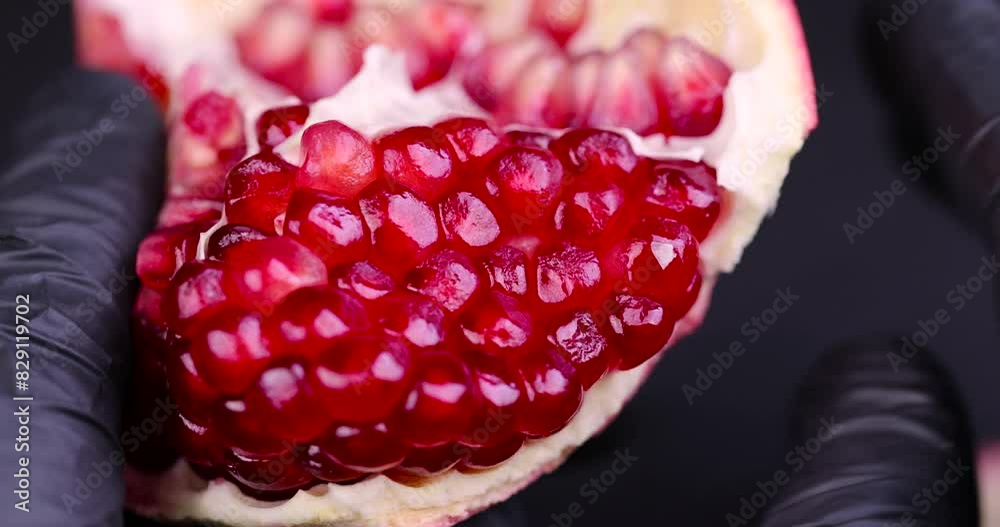 red grains of peeled pomegranate fruit, large sweet and juicy pomegranate seeds on a table made of black slate