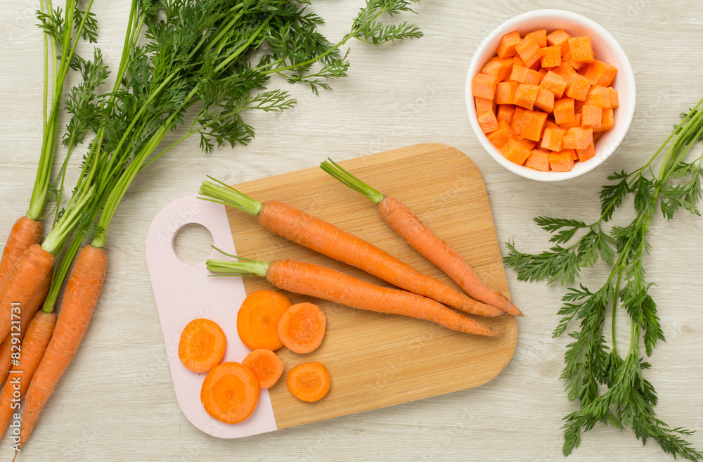 Bunch of fresh carrots with sliced ones on wooden background, top view Bunch of fresh carrots with sliced ones on wooden background, top view