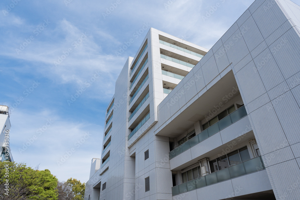 Obraz premium 広い建物の病院、青空に伸びる病棟、大学病院