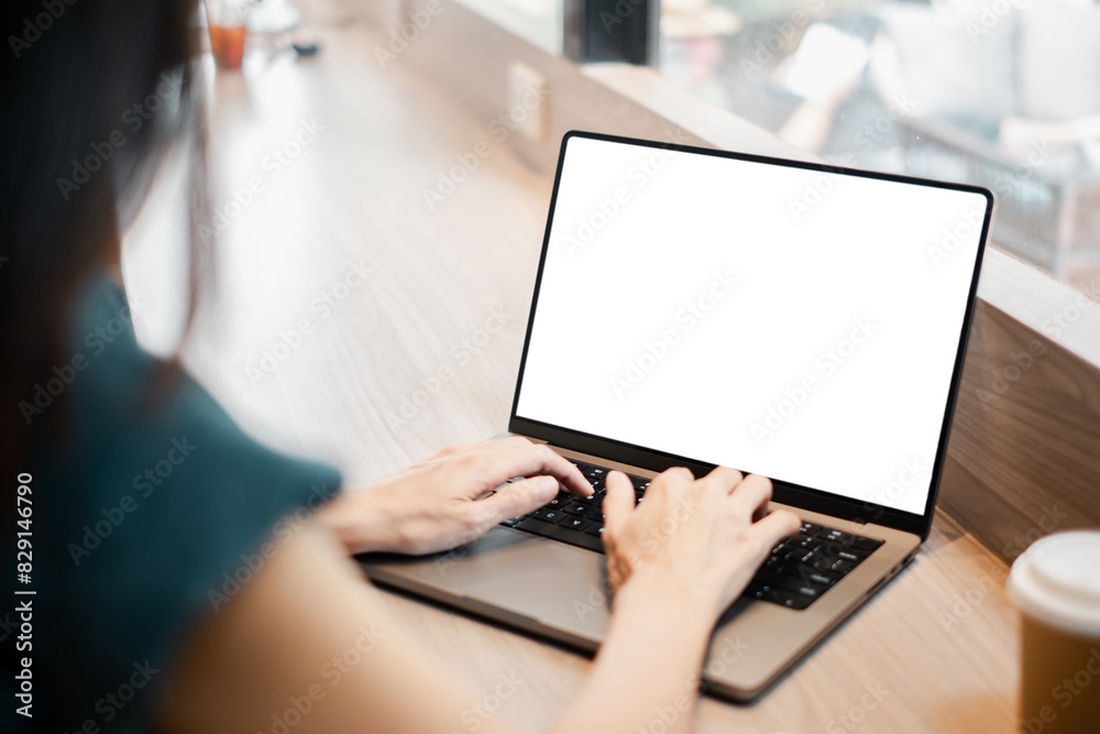 A woman is typing on a laptop with a blank screen. She is sitting at a table with a cup of coffee in front of her. Concept of productivity and focus A woman is typing on a laptop with a blank screen. She is sitting at a table with a cup of coffee in front of her. Concept of productivity and focus
