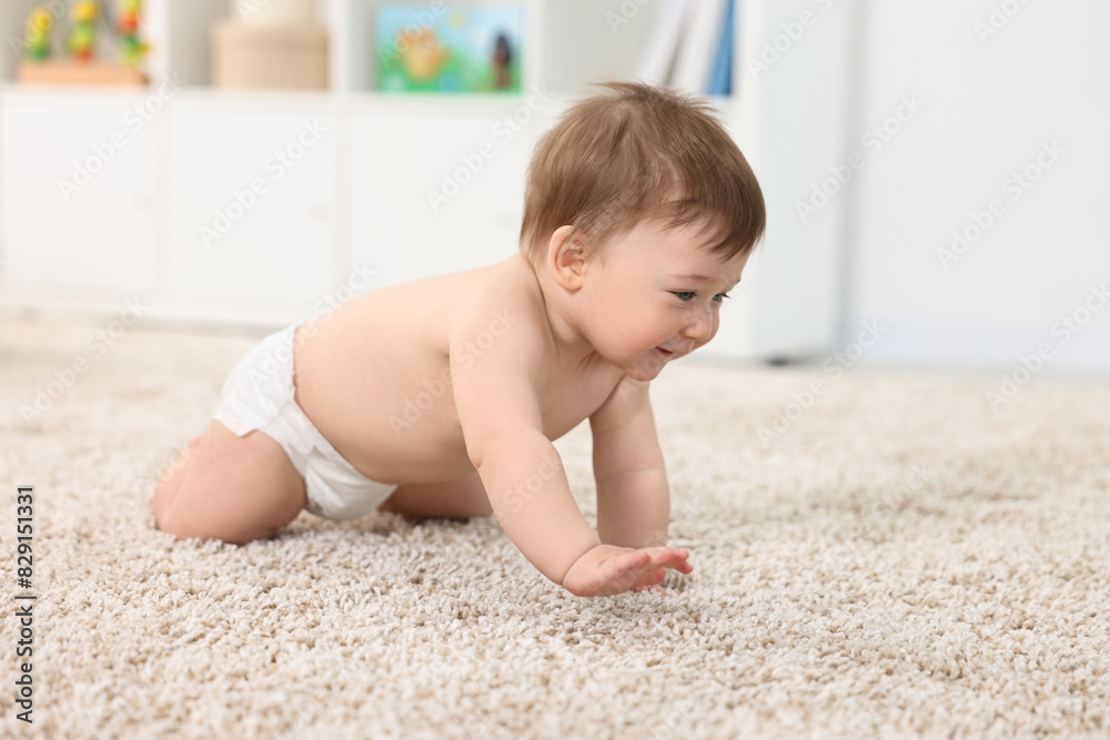 Cute baby boy crawling on carpet at home