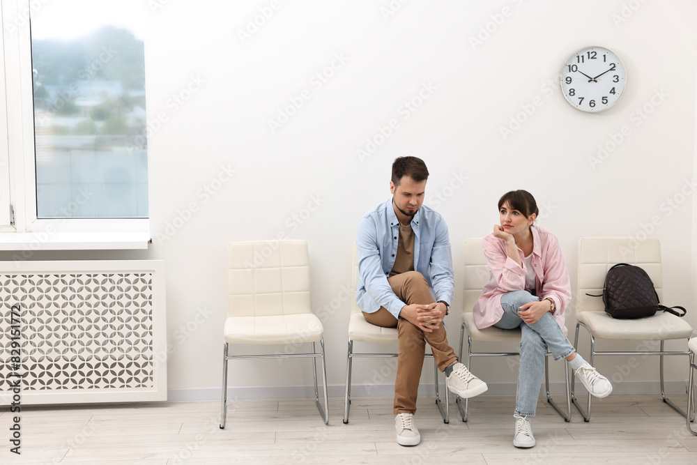 Man and woman waiting for appointment indoors Man and woman waiting for appointment indoors