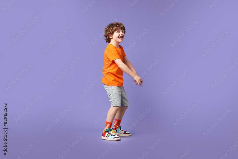 Happy little boy dancing on violet background Happy little boy dancing on violet background