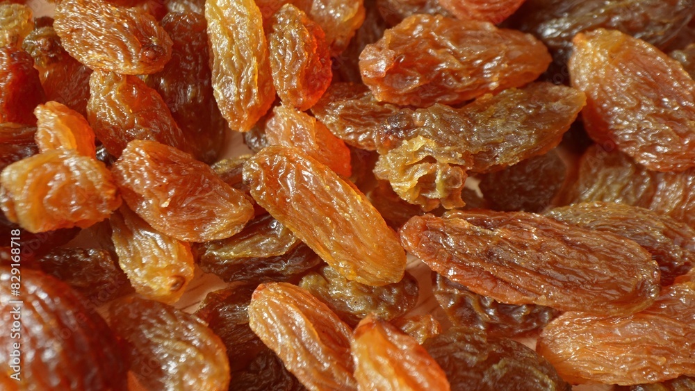 In a mesmerizing close-up, golden-brown raisins glisten with natural sweetness. Each textured surface tells a story of preserved flavor and richness, their translucent glow captivating the senses.

