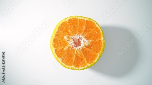 The glistening surface of this succulent orange half radiates a golden hue  its segments brimming with citrusy zest  a promise of tangy refreshment. Orange background.   