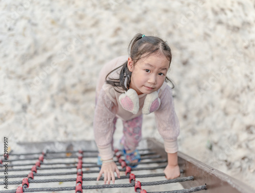 Little girl play in climbing a rock wall outdoor