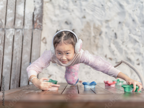 Little girl play in climbing a rock wall outdoor