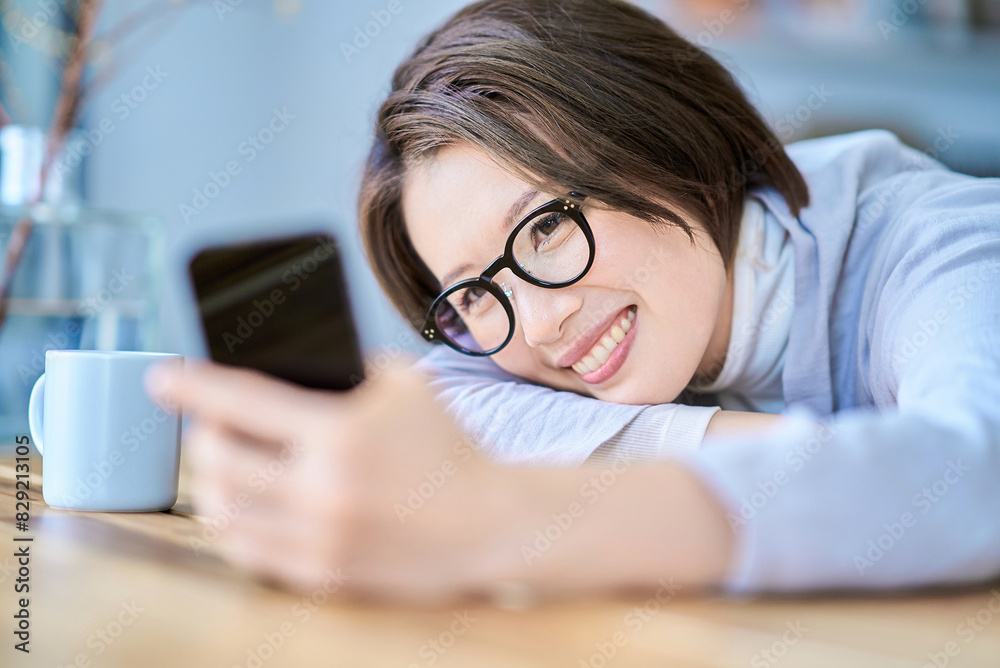 部屋でスマートフォンを操作する女性 部屋でスマートフォンを操作する女性