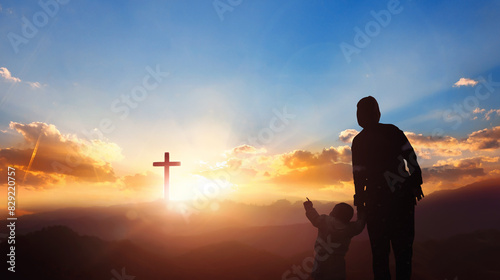 Silhouette mom and son looking for the cross on meadow autumn sunrise background