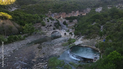 People bathing in a natural hot spring spa. Medieval bridge over the river leading to the water. Albania. Benja Thermal Baths photo