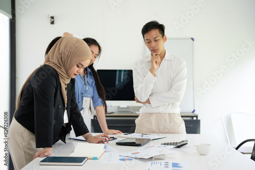 Group of Asian business people planning a project, discussing work documents.