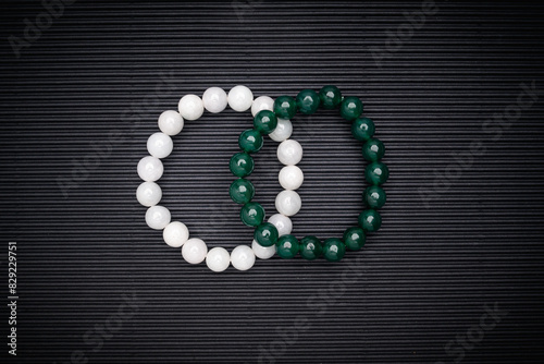 Green and white jade bead bracelets on a black background.