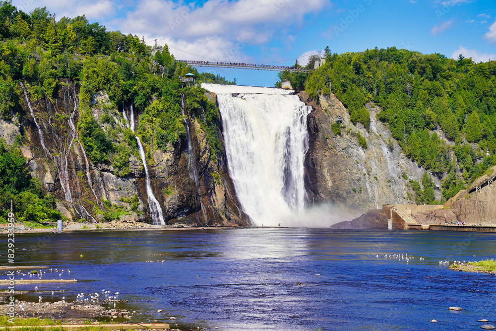 Obraz premium Magnificent view of the Montmorency Falls and the suspension bridge on a bright summer day with blue skies near Quebec city, the capital of Quebec province,Canada