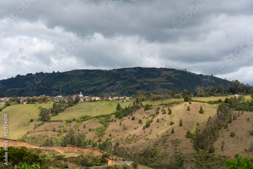 Church in a town seen in the distance surrounded by country landscape with mountains in Colombia.