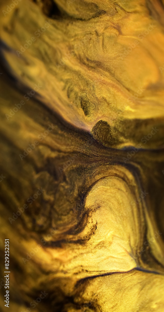 Sparkling ink spill. Glitter fluid texture. Defocused black yellow golden color shimmering sand particles acrylic paint mix emulsion liquid flow abstract art background.