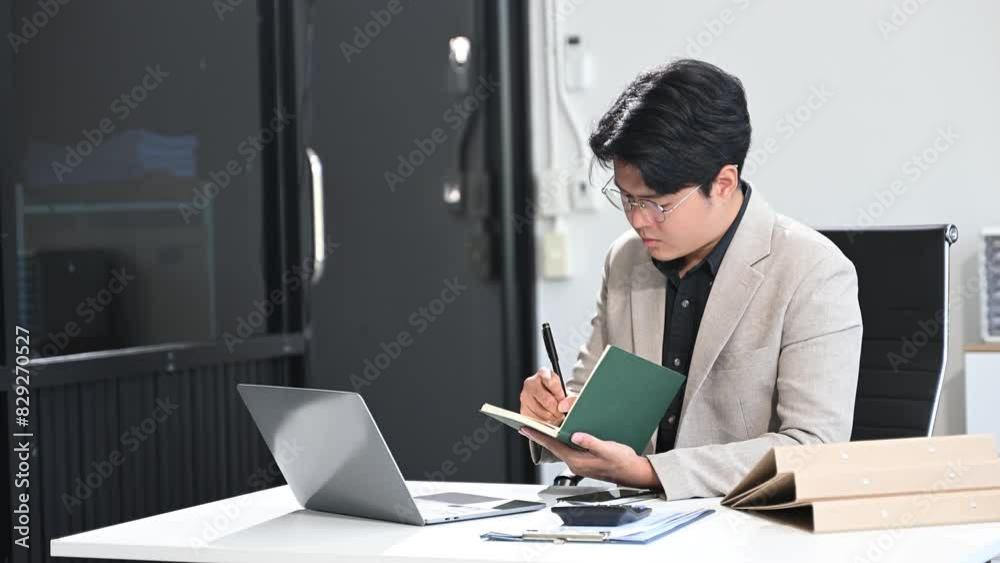Young businessman working at office with laptop, tablet and taking notes Young businessman working at office with laptop, tablet and taking notes