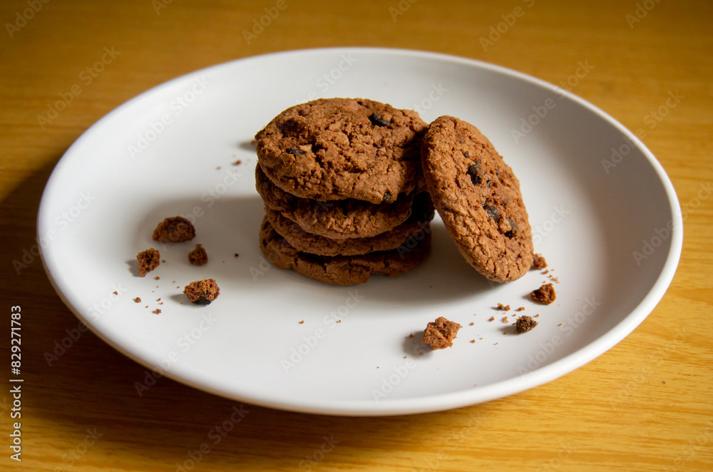 sweet chocolate biscuits on a white plate with a wooden patterned background sweet chocolate biscuits on a white plate with a wooden patterned background