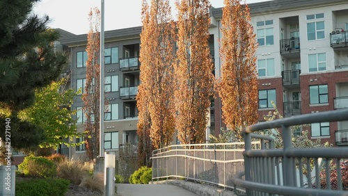 Modern residential building exterior with autumn trees and walkway