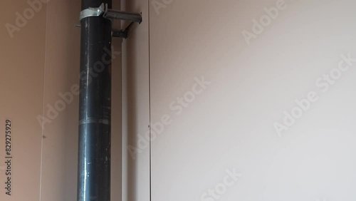 Black pipe running along beige wall in a minimalistic interior
