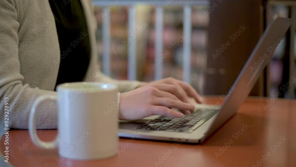 A close-up view of a woman's hands typing on a laptop, with a cup of matcha tea nearby on a vibrant red table, symbolizing productivity and a healthy lifestyle.