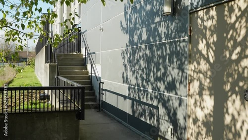 Shaded pathway and stairs beside a building with tree shadows