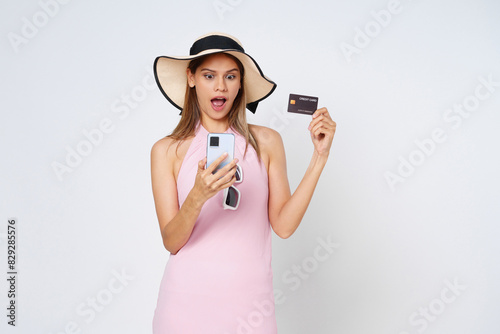 Excited asian woman using credit card and smartphone app, paying on website via mobile phone, white background.