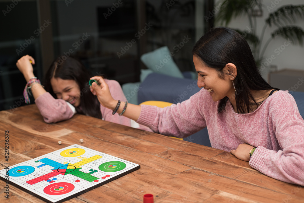 Fototapeta premium Mother and daughter having fun playing ludo board game