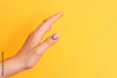 Bruise under the nail with manicure on the thumb against a yellow background.