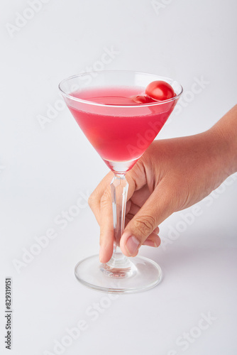 Hand holding Pink daisy cocktail in transparent glass isolated on white background.