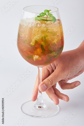 Hand holding glass of mojito cocktail isolated on white background.