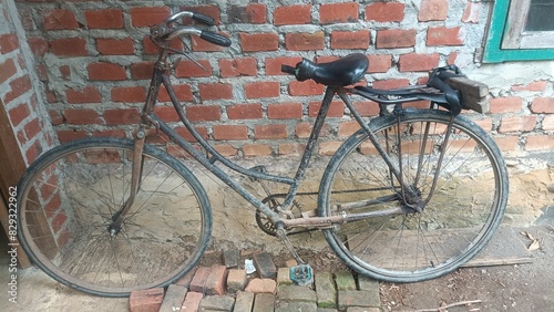 Traditional Indonesian means of transportation, an old onthel bicycle leaning against the wall of a new brick house photo