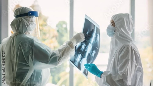 A nurse wearing protective equipment hands an X-ray film to a doctor. The concept reflects COVID-19 KP1. photo