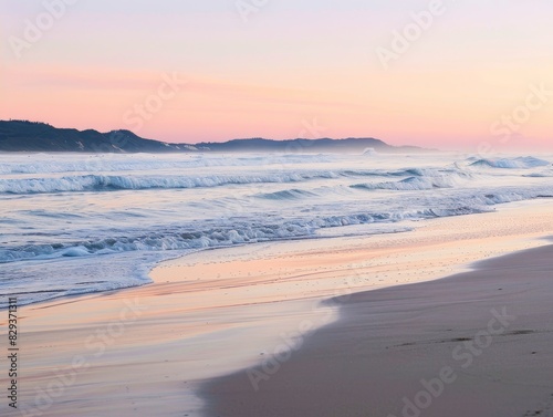 A serene beach scene at dawn with soft waves gently lapping the shore and a colorful sunrise in the background