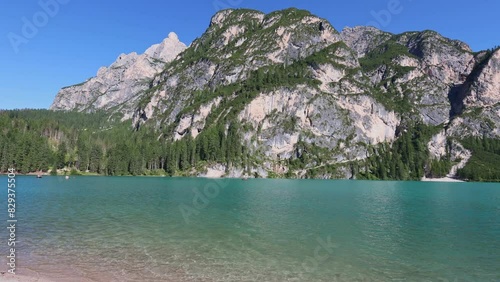 Spectacular scene of serene turquoise waters of natural Lake Braies under summer sun surrounded by lush greenery and rocky mountains in Prags Dolomites in South Tyrol, Italy photo