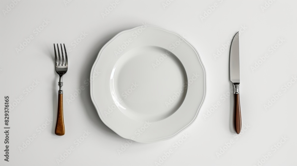 Top-down view of a white plate on a table, with a fork and knife positioned symmetrically, creating a serene scene on a clean white background Top-down view of a white plate on a table, with a fork and knife positioned symmetrically, creating a serene scene on a clean white background