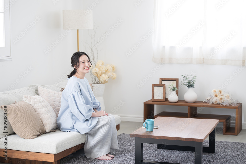 Asian (Japanese) woman relaxing in living room, full length Asian (Japanese) woman relaxing in living room, full length