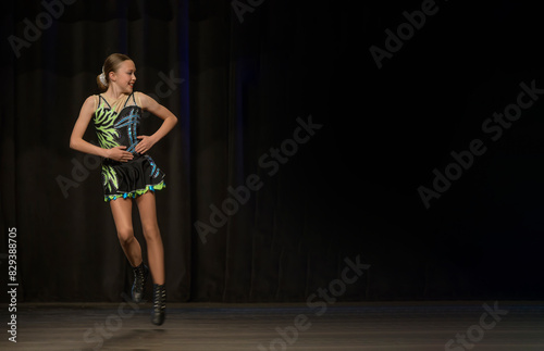 Young teenage dancer in joyful movement on stage, Place for text, dark curtain
