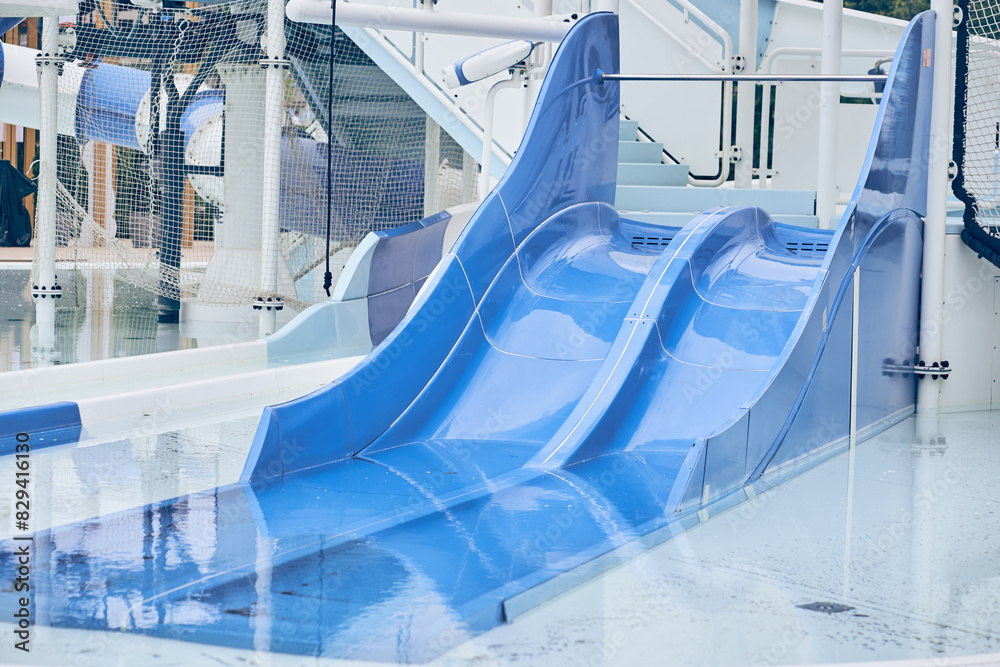 Obraz premium A water park, a bright blue slide with a swimming pool. A water park without people on a summer afternoon in the morning with space to copy. High quality photo