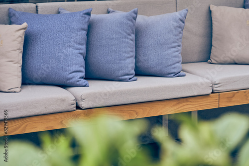 Outdoor patio with sofa and cushions. A blurred green plant in an outdoor garden. Sofa with copy space. High quality photo