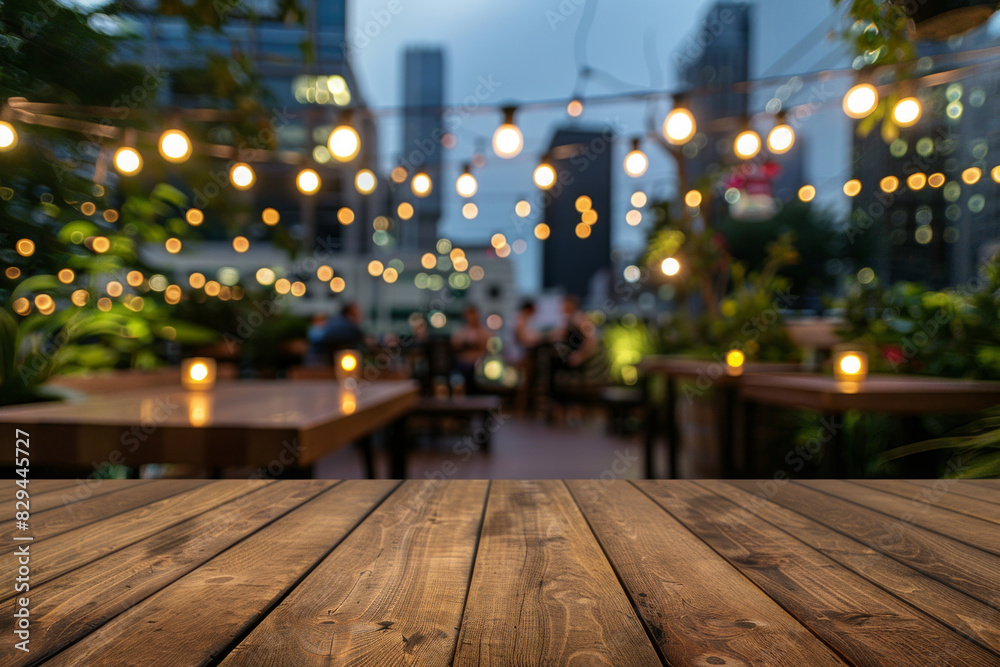 A wooden bar top in the foreground with a blurred background of an urban rooftop bar. The background includes stylish seating, plants, string lights, a panoramic city view. A wooden bar top in the foreground with a blurred background of an urban rooftop bar. The background includes stylish seating, plants, string lights, a panoramic city view.