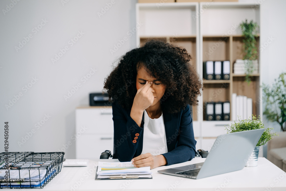 Frustrated young businesswoman working on a laptop computer sitting at his working place