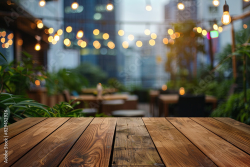 A wooden bar top in the foreground with a blurred background of an urban rooftop bar. The background includes stylish seating  plants  string lights  a panoramic city view.