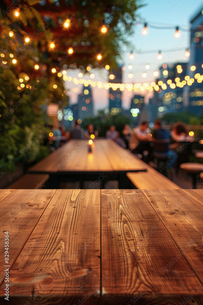 A wooden bar top in the foreground with a blurred background of an urban rooftop bar. The background includes stylish seating, plants, string lights, a panoramic city view.