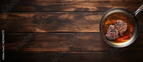 A copy space image of a delicious piece of fried meat along with hot oil sitting on a scratched timber tabletop captured from above using a metal frying pan
